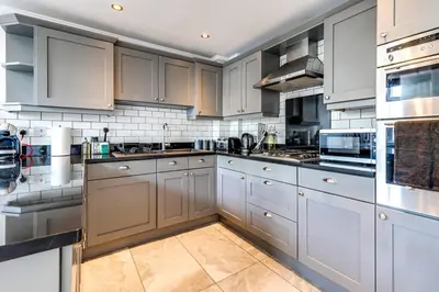a large kitchen with white cabinets and appliances at Entire 3 Bedroom House Contractors Families Relocators in Ware