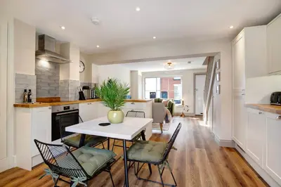 a kitchen and living room with a table and chairs at Beautifully refurbished cottage in lower Wivenhoe. in Wivenhoe
