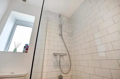 a bathroom with a shower with white tiles at Beautifully refurbished cottage in lower Wivenhoe. in Wivenhoe