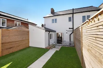 a garden with a fence and green grass at Beautifully refurbished cottage in lower Wivenhoe. in Wivenhoe