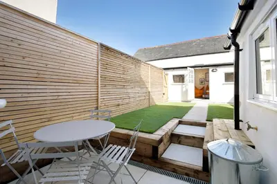 a patio with a table and chairs and a fence at Beautifully refurbished cottage in lower Wivenhoe. in Wivenhoe
