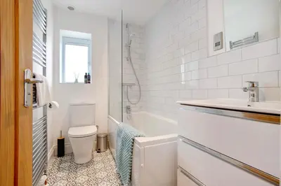 a white bathroom with a toilet and a sink at Beautifully refurbished cottage in lower Wivenhoe. in Wivenhoe