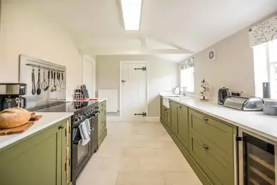 a kitchen with green cabinets and white counter tops at Gardeners Cottage - Nowton Park in Bury Saint Edmunds