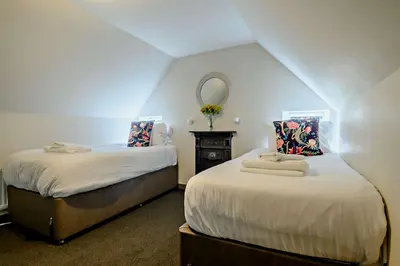 two beds in a small room with a mirror at Gardeners Cottage - Nowton Park in Bury Saint Edmunds
