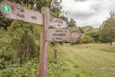 a wooden sign on the side of a road at Gardeners Cottage - Nowton Park in Bury Saint Edmunds