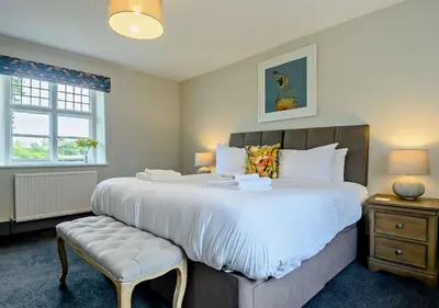 a bedroom with a large bed and a chair at Gardeners Cottage - Nowton Park in Bury Saint Edmunds
