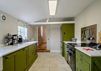a kitchen with green cabinets and a stove top oven at Gardeners Cottage - Nowton Park in Bury Saint Edmunds