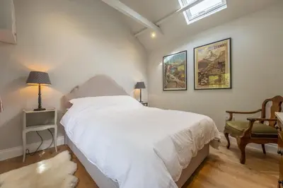 a bedroom with a white bed and a chair at Weavers Mark Cottage in Diss