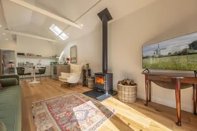a living room with a fireplace and a flat screen tv at Weavers Mark Cottage in Diss