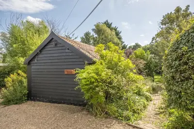 a small black shed next to some bushes at Weavers Mark Cottage in Diss