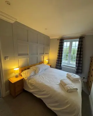 a bedroom with a large white bed with two lamps at Hall Farm Cottage, Barham in Ipswich