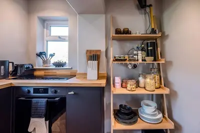a kitchen with a stove and a shelf with dishes at Key Cottage, Orford in Woodbridge