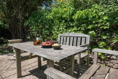 a picnic table with a bowl of fruit and a chair at Key Cottage, Orford in Woodbridge