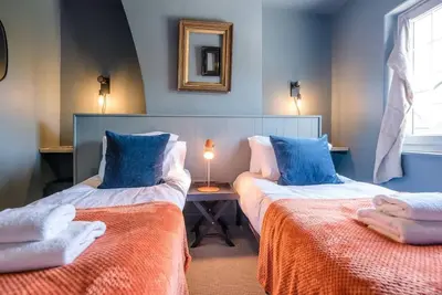 two beds in a room with blue walls at Key Cottage, Orford in Woodbridge