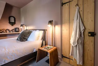 a bedroom with a bed and a door with a table at Key Cottage, Orford in Woodbridge
