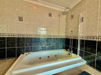 a bath tub in a bathroom with blue tiles at 6 Bedroom House - DISC0UNTS - Pool Table, Parking, Contractors, Group, Family in Colchester
