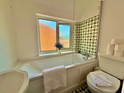 a bathroom with a tub and a toilet and a window at 6 Bedroom House - DISC0UNTS - Pool Table, Parking, Contractors, Group, Family in Colchester