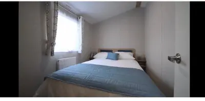 a bedroom with a bed with a blue blanket and a window at Ultimate serene getaway in East Mersea