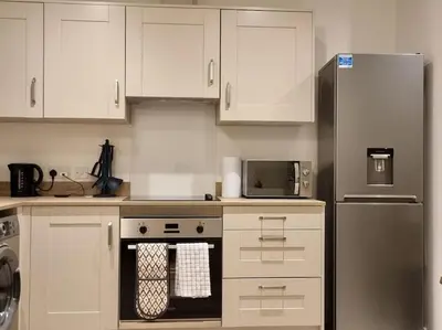 a kitchen with white cabinets and a stainless steel refrigerator at Modern 2bedroom House in Ipswich Suffolk in Ipswich