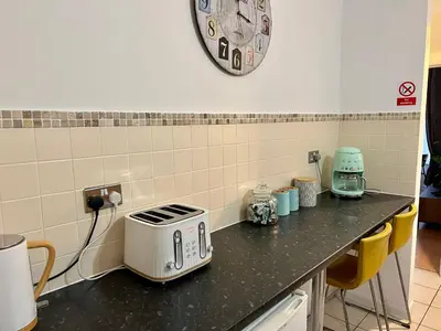 a kitchen counter with a toaster and a clock on the wall at Fig Tree Central Cambridge Apartment Walk to Colleges & River Cam in Cambridge