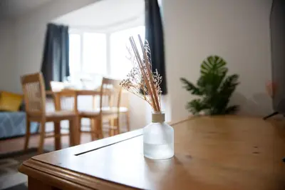a white vase with dried flowers sitting on a table at Tillyard Retreat, Ground Floor Apartment Cambridge in Cherry Hinton