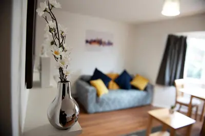 a vase with flowers on a table in a living room at Tillyard Retreat, Ground Floor Apartment Cambridge in Cherry Hinton