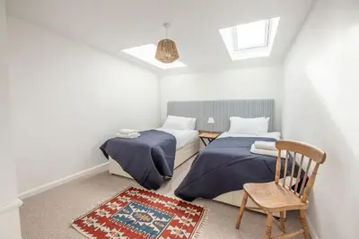 a bedroom with two beds and a chair and a rug at Print Rooms, Leiston in Leiston