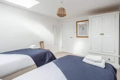 a white bedroom with two beds and a cabinet at Print Rooms, Leiston in Leiston