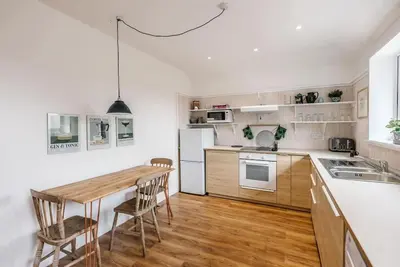 a kitchen with white appliances and wooden floors and a wooden table at Print Rooms, Leiston in Leiston