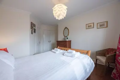 a bedroom with a white bed and a chandelier at The Little Hopton, Saxmundham in Saxmundham