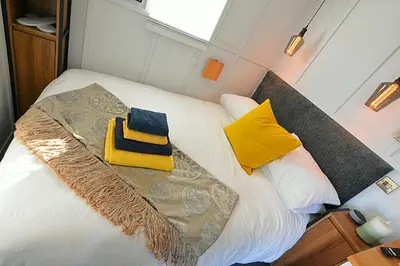 a bed in a small room with yellow and blue pillows at Beautiful shepherd’s hut in Newmarket