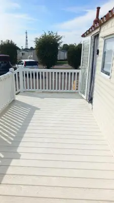 a wooden walkway next to a house with a fence at Holiday Caravan in Clacton-on-Sea