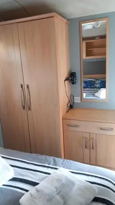 a bedroom with a bed and a dresser and a mirror at Holiday Caravan in Clacton-on-Sea