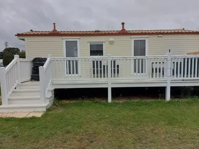 a house with a white porch and a white railing at Holiday Caravan in Clacton-on-Sea