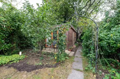 a garden with an arbor with a fence and a building at Peaceful Oasis 3 Beds House with Garden and Parking in Cambridge