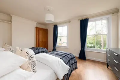 two beds in a bedroom with two windows at Peaceful Oasis 3 Beds House with Garden and Parking in Cambridge