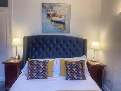 a bed with a blue headboard and two nightstandumentsuments at Seaside private garden in Leigh-on-Sea