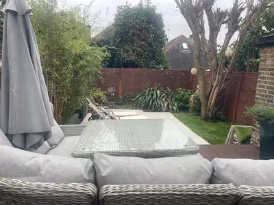 a patio with a couch and a table and an umbrella at Seaside private garden in Leigh-on-Sea