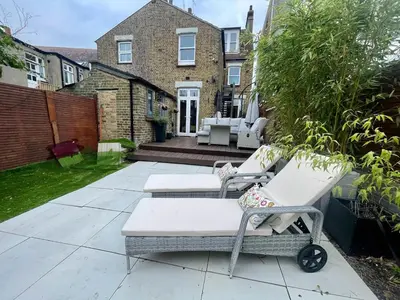 a patio with two lounge chairs and a house at Seaside private garden in Leigh-on-Sea