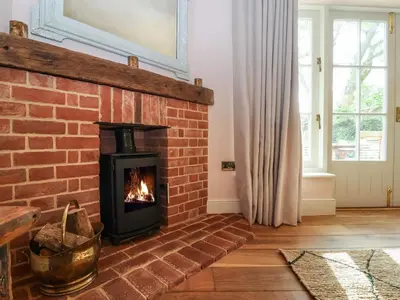 a fireplace in a living room with a brick wall at Rookery Cottage in Saxmundham