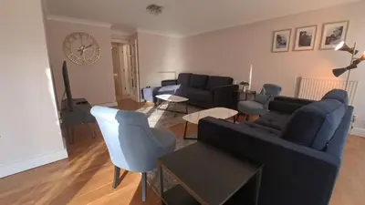 a living room with a couch and chairs and a clock at Lady Jane Court in Trumpington