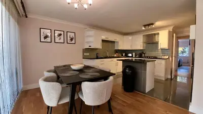 a kitchen with a table and some chairs and a counter at Lady Jane Court in Trumpington