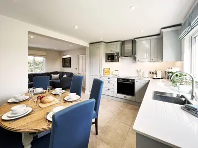 a kitchen and dining room with a table and blue chairs at Dell View by The Suffolk Cottage Collection in Bentley