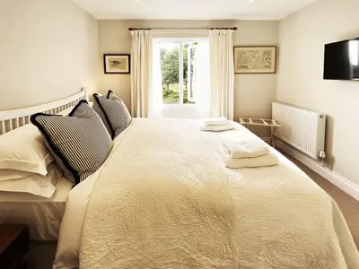 a bedroom with a large white bed with a window at Dell View by The Suffolk Cottage Collection in Bentley
