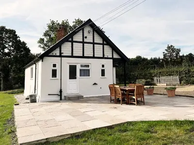 a small white shed with a table and chairs at Dell View by The Suffolk Cottage Collection in Bentley