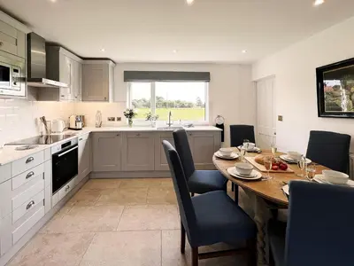a kitchen with a wooden table and a dining room at Dell View by The Suffolk Cottage Collection in Bentley