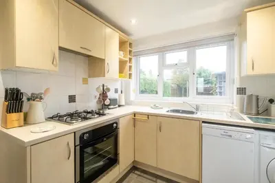 a kitchen with white cabinets and a stove top oven at Hollybobs in Leiston