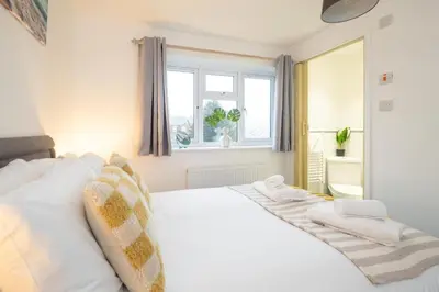 a white bed in a room with a window at Hollybobs in Leiston