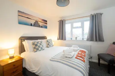 a bedroom with a bed and a chair and a window at Hollybobs in Leiston