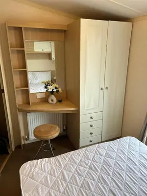 a bedroom with a bed and a desk and a cabinet at Havah’s in Saint Osyth